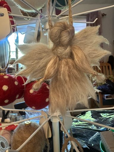 A handcrafted angel decoration with a light blonde hair and fluffy wings.