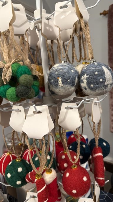 Colourful decorative ornaments in various shapes and sizes, hanging on tags.