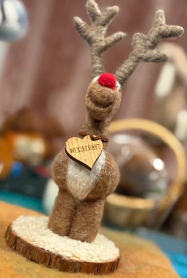 A felted reindeer figurine with a red nose and a heart-shaped tag that says "Love".