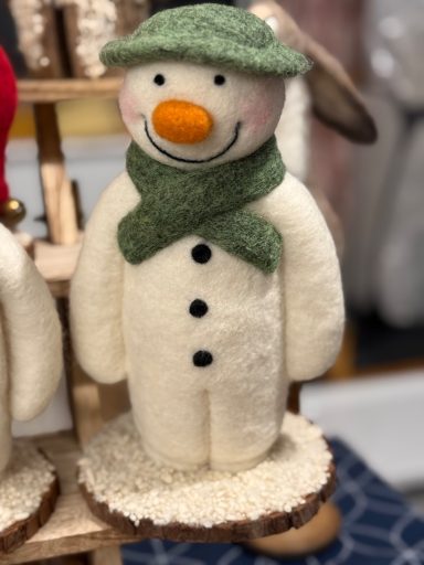 A decorative snowman with a green scarf, orange nose, and black buttons.