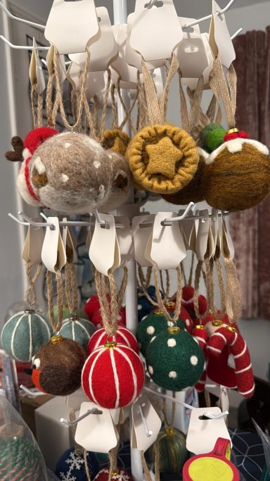 Colourful handmade ornaments in various shapes hanging on a display stand.