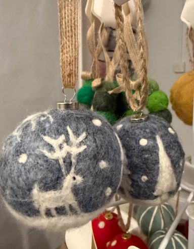 Blue and white decorative baubles featuring a deer and tree design, adorned with greenery.