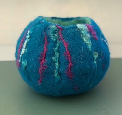 Round, felted bowl in vibrant blue with decorative pink and turquoise accents.